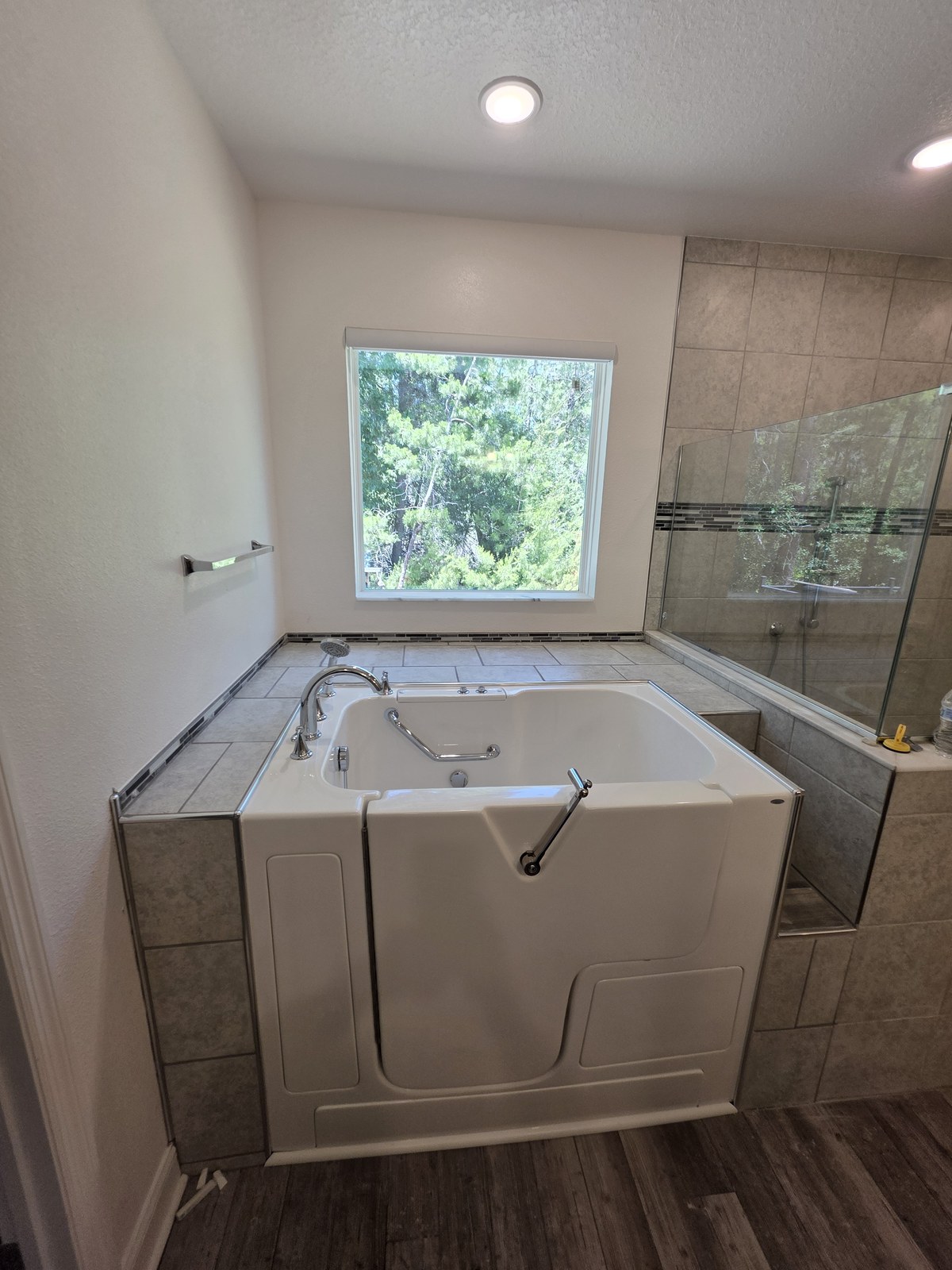 Completed walk-in bathtub installation with tiled surround built-in seat and grab bars