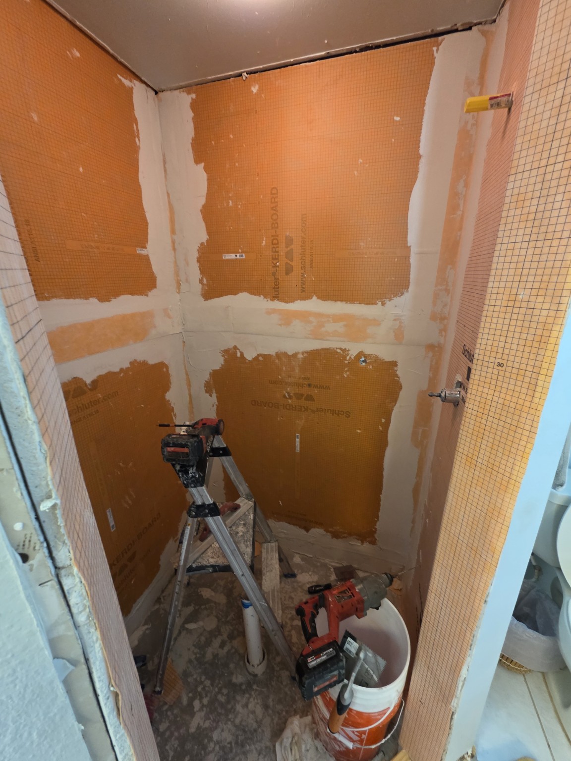 Shower wall preparation with orange backer boards before base installation
