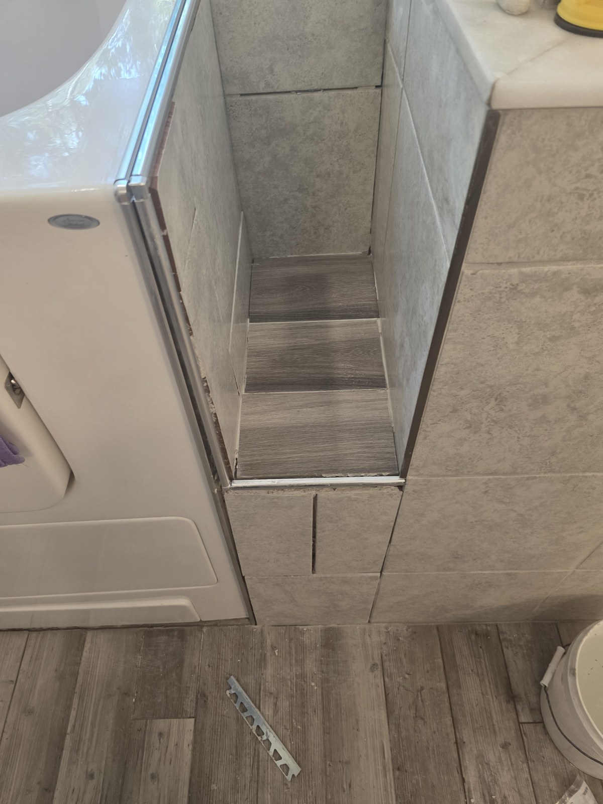 Lower-entry step and tiled surround beside a walk-in bathtub